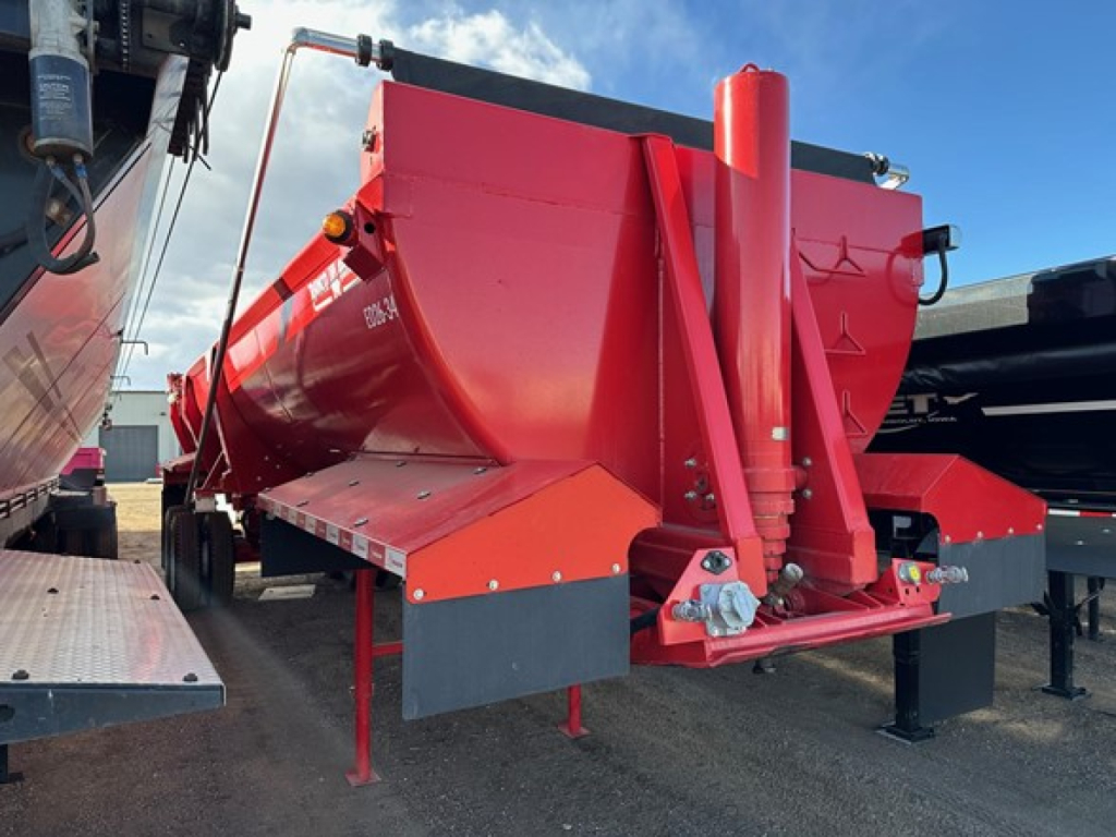 Ranco rock end dump trailer in red showing hydraulic lift and chute with support legs and mounting frame.
