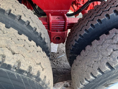 Truck trailer hitch area with dual rear tires and red suspension/u-bolts visible in a rock end dump trailer.