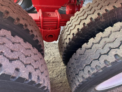 Dump trailer tires and red undercarriage components of a 2025 Ranco Rock End Dump showing dual rear tires and suspension bracket.