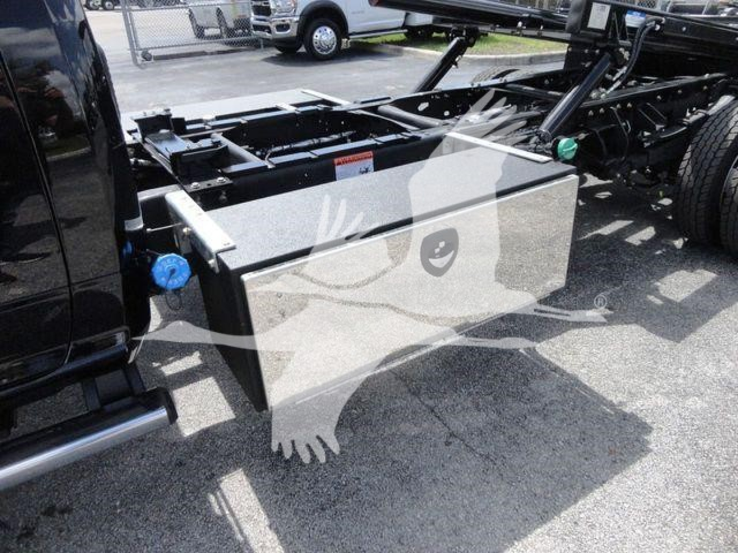 Vehicle chassis area with a large rectangular black battery/box mounted under the frame near the truck cab; visible valve stems and frame components.
