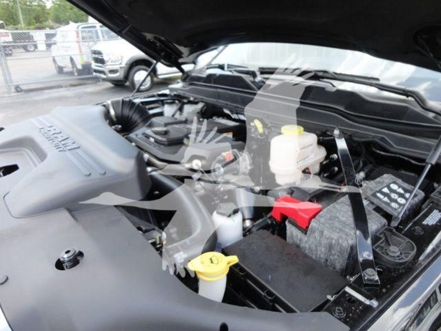 Ram 5500 engine bay showing engine block, battery, coolant reservoir, and yellow-capped fluid reservoirs under the hood.