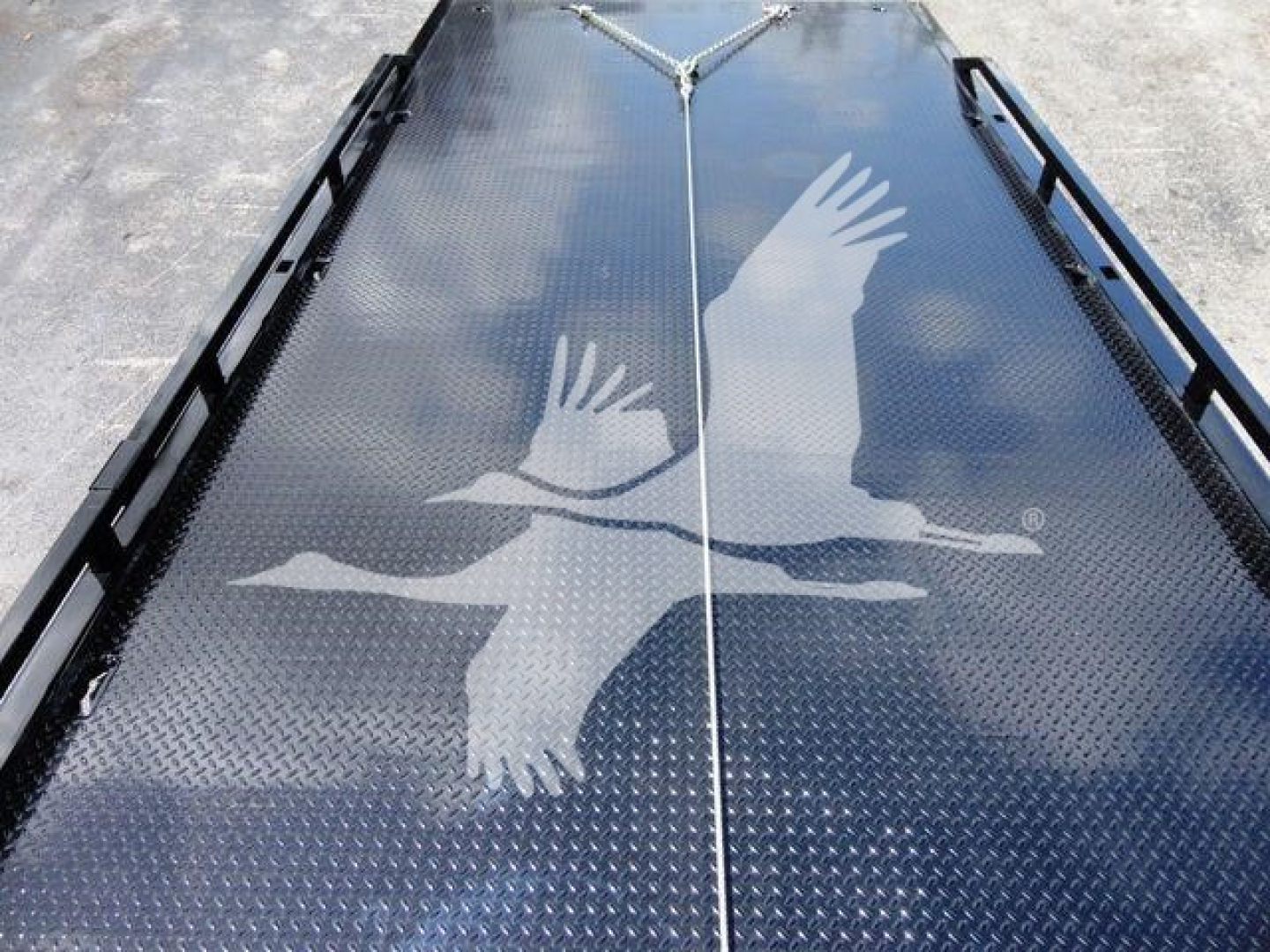 Flatbed truck bed with diamond plate surface featuring a large white graphic of two geese in flight along the center seam.