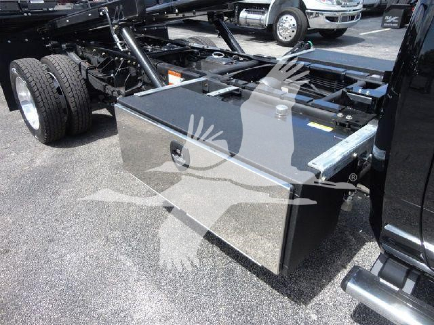 Ram 5500 rollback truck chassis with a shiny aluminum tool box mounted behind the cab, dual rear wheels visible, hydraulic chassis frame, and metal fuel tank cover.