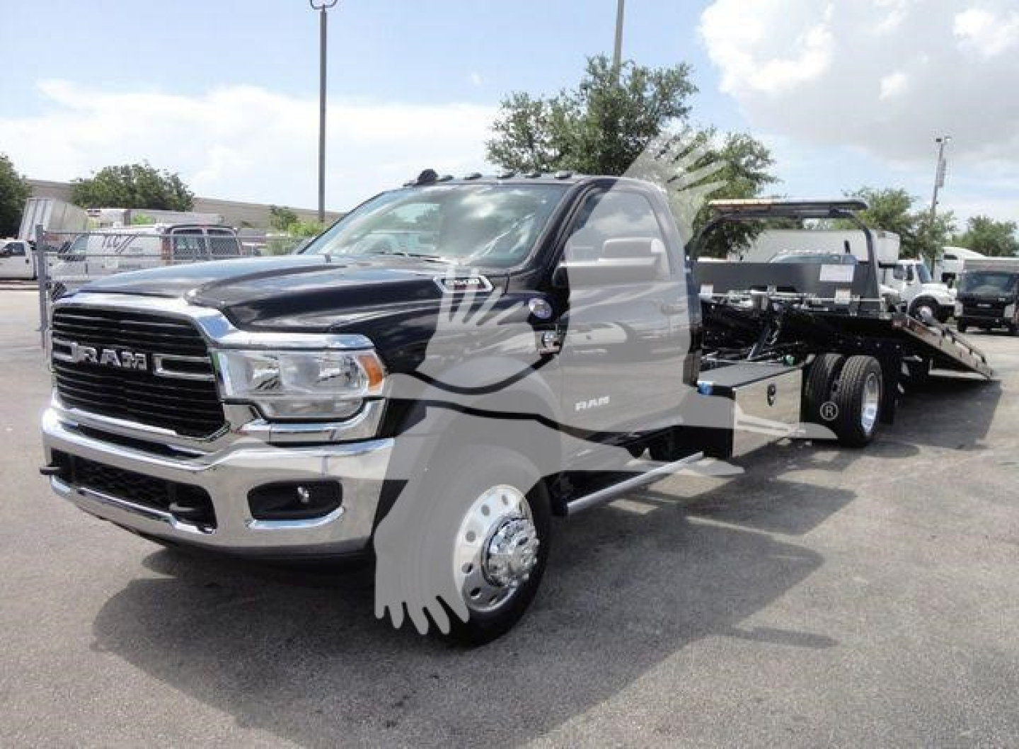 Ram 5500 rollback truck in black with chrome grille and front fender showing RAM badge, wheel, and flatbed tow configuration.