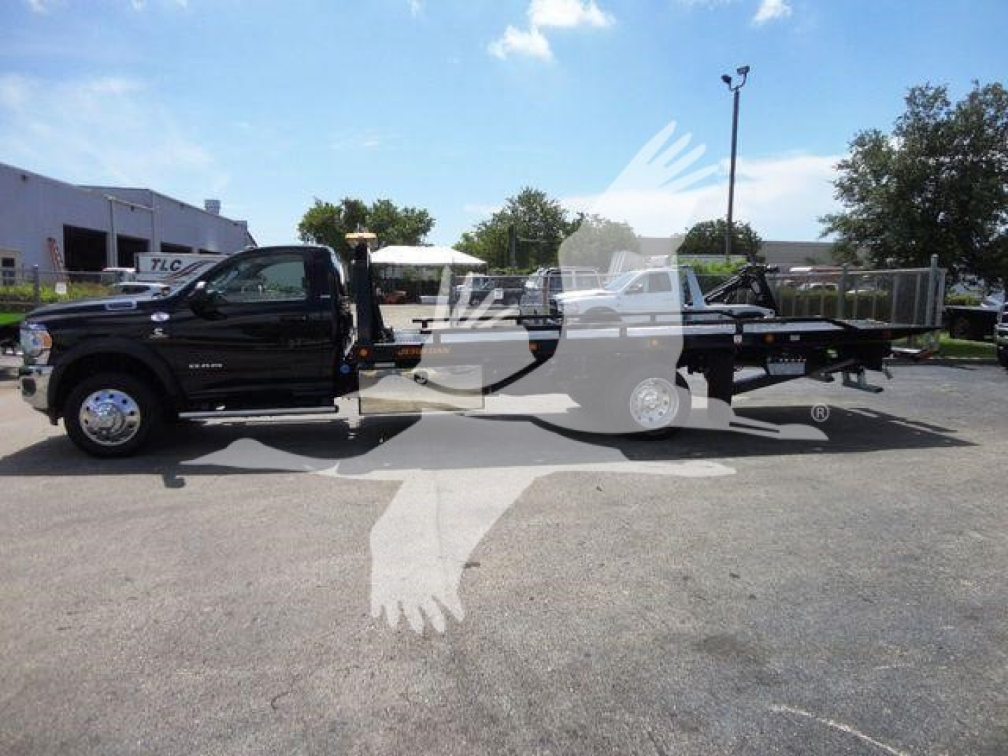Ram 5500 SLT pickup truck with rollback tow bed side view showing black exterior and equipment for towing.