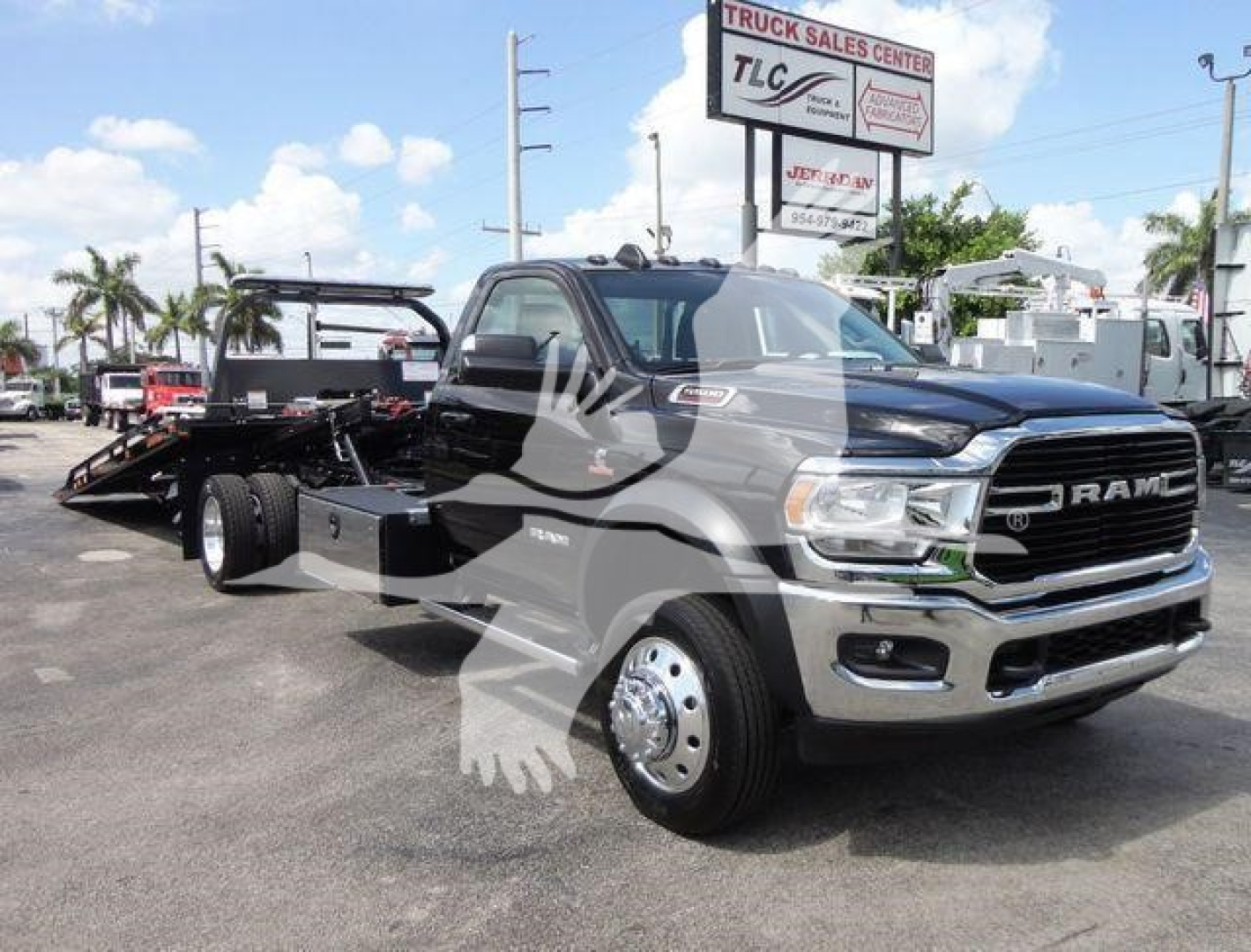 Ram 5500 rollback tow truck in showroom lot with chrome grille and dual wheels, front angled view, RAM badge visible