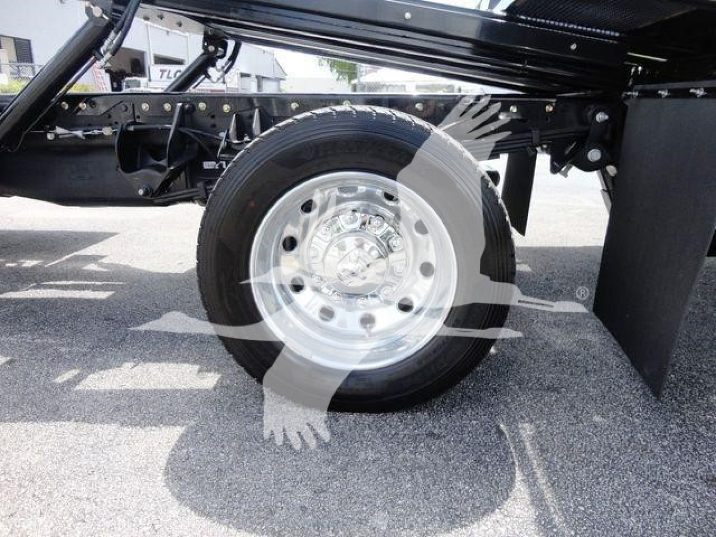 Truck wheel and undercarriage with a polished steel rim visible, portion of suspension and frame in view.