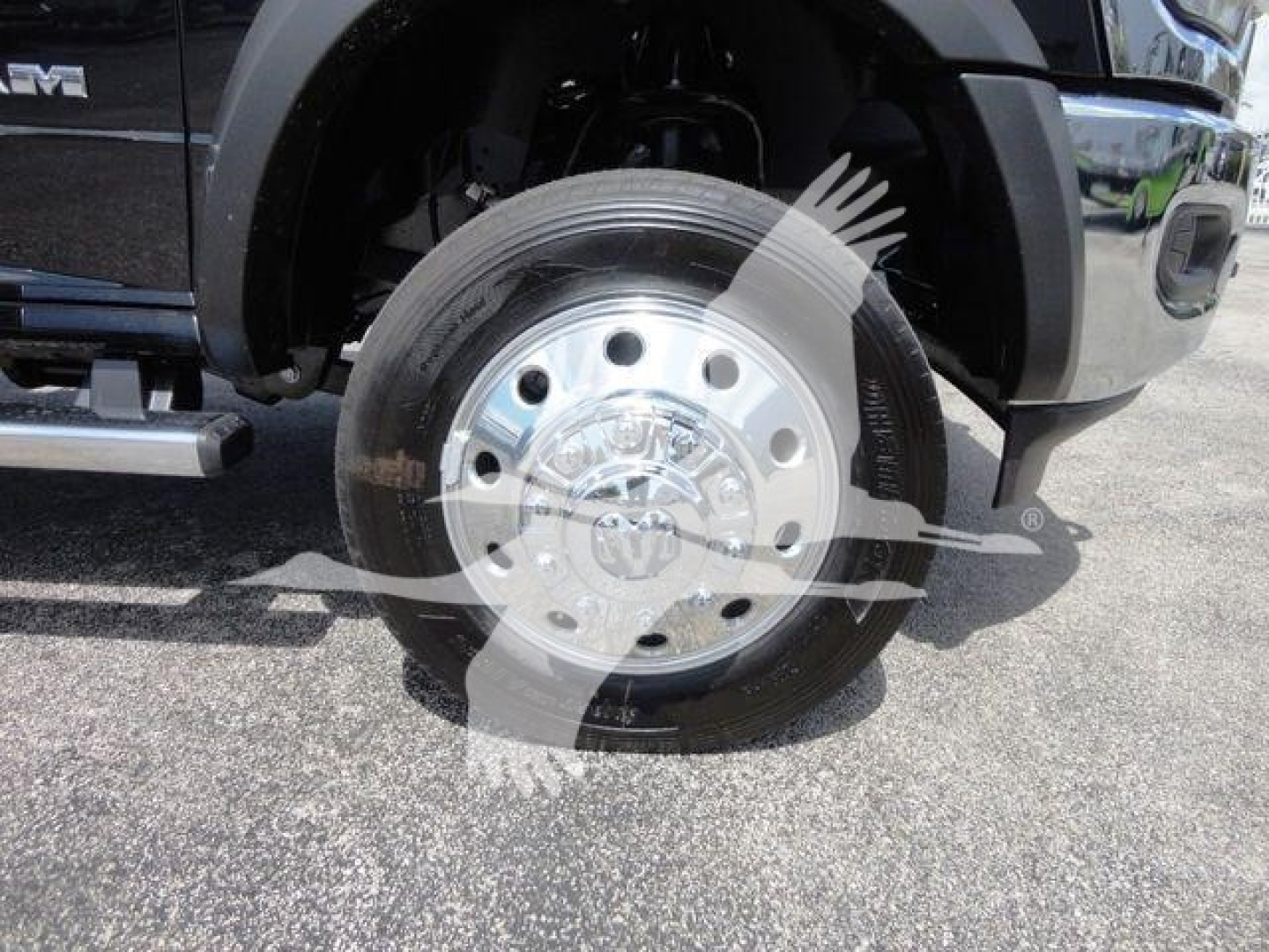 Ram truck front wheel showing chrome hub with multiple lug nuts and star emblem, tire mounted, fender and side step visible.