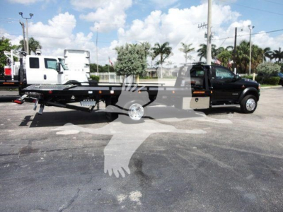 Tow truck bed with Ram 5500 SLT under blue sky, stock number J67261, rollback category, new truck.
