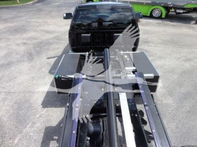 Ram 5500 rollback chassis with flatbed and wheel-lift system, showing metal rails and control boxes.