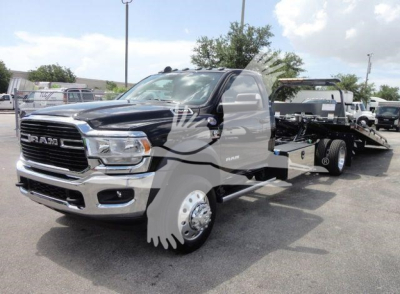 Ram 5500 rollback truck in black with chrome grille and front fender showing RAM badge, wheel, and flatbed tow configuration.