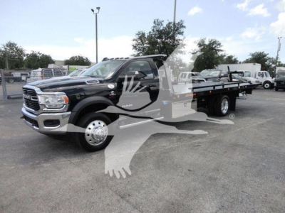2024 Ram 5500 SLT roll-back tow truck with flatbed, black cab, front grille, chrome bumper, dual rear wheels, dealership lot in background.