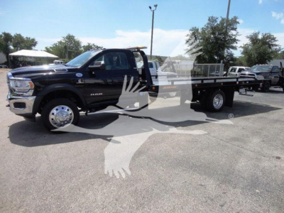 2024 Ram 5500 SLT side view of rollback truck with flatbed displaying wide dual rear wheels and chrome wheels