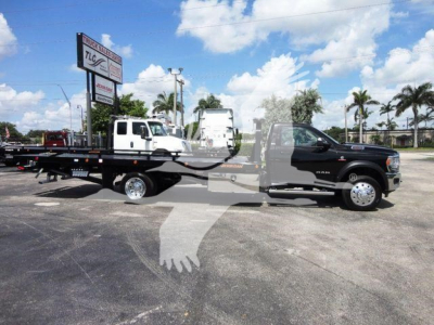 Ram 5500 SLT tow truck with rollback bed in a dealership lot showing the forward cab and long flatbed.
