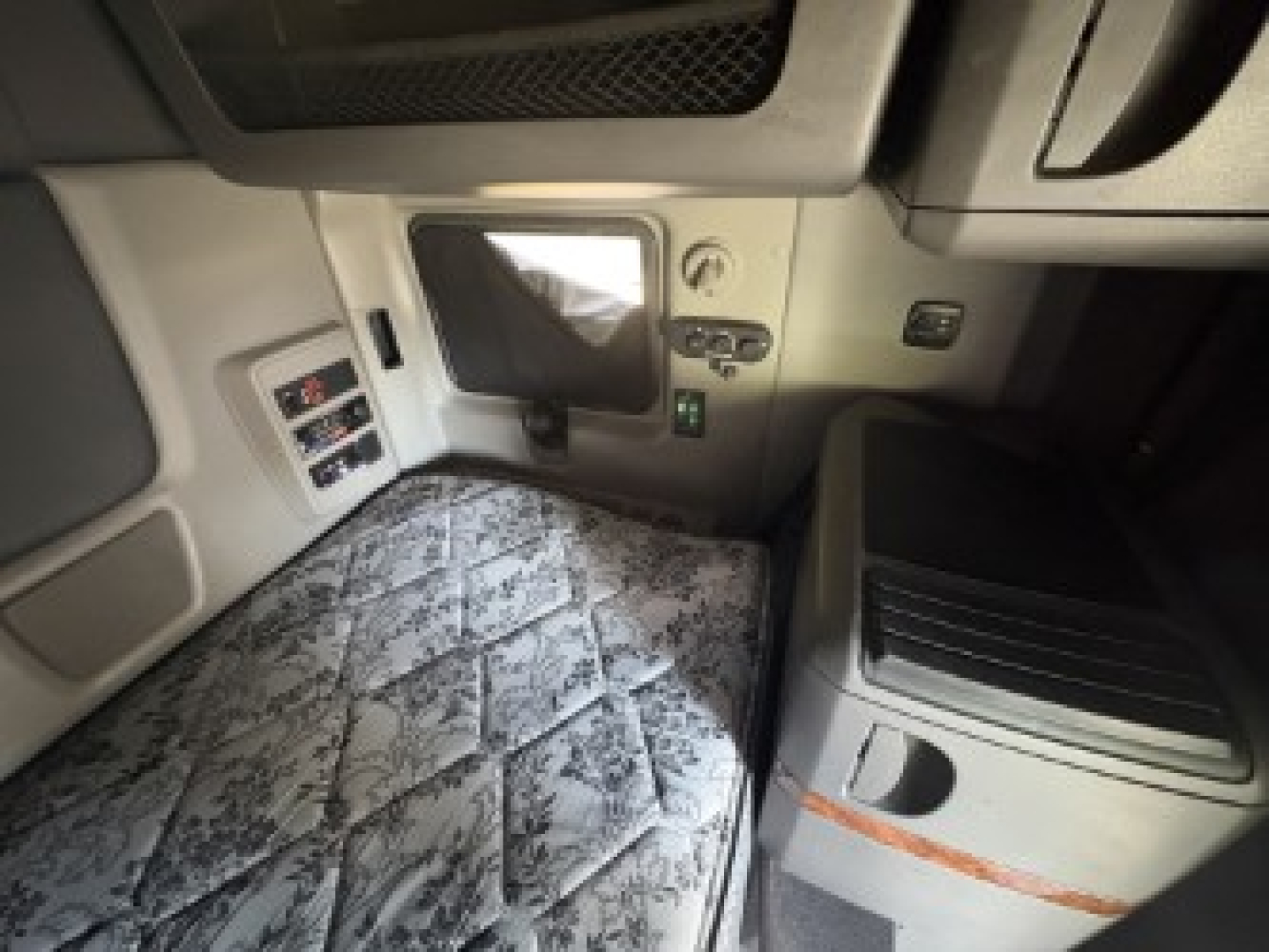 Truck cab interior showing sleeper area with quilted mattress, control panels, and storage compartments visible in a 2021 International LT625 truck.