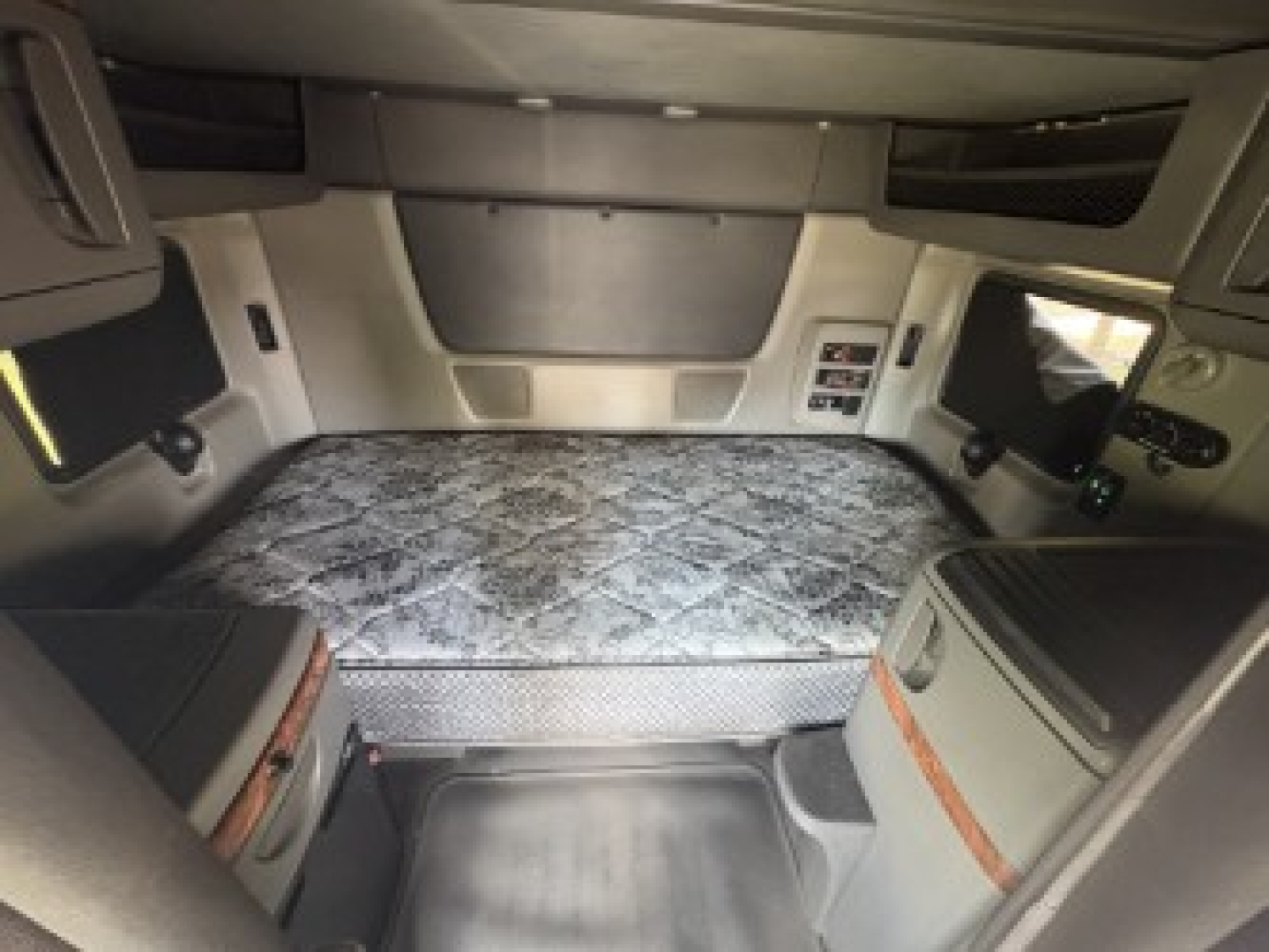 Cab interior of a used 2021 International LT625 sleeper truck showing a raised sleeper bed and side panels with storage compartments.