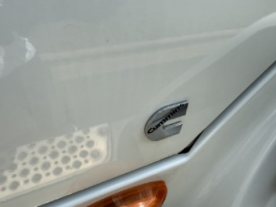 Trucks wheel area showing International logo emblem on side of a cab, with treaded step and orange turn signal lens.