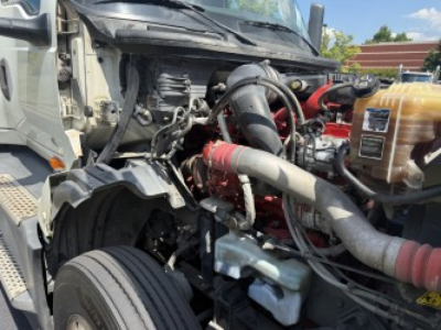 Truck engine bay showing LT625 International with visible radiator, coolant reservoir, red turbo/intercooler piping, and various hoses.