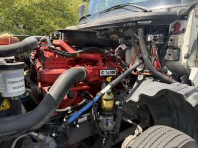 Engine bay of 2021 International LT625 showing red engine, hoses, yellow oil filter, and various components in view.