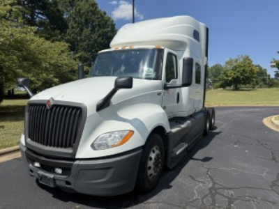 Truck cab with a large black grille and white exterior showing a sleeper tractor for International LT625, front view in a parking lot.