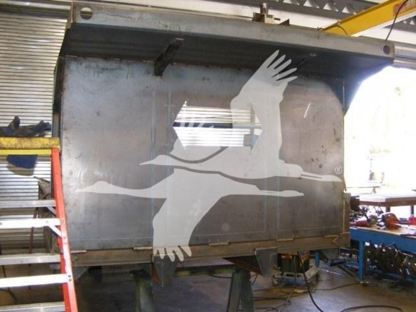 Dump truck bed showing large graphic of seagull with wings spread on side panel, in a workshop setting.