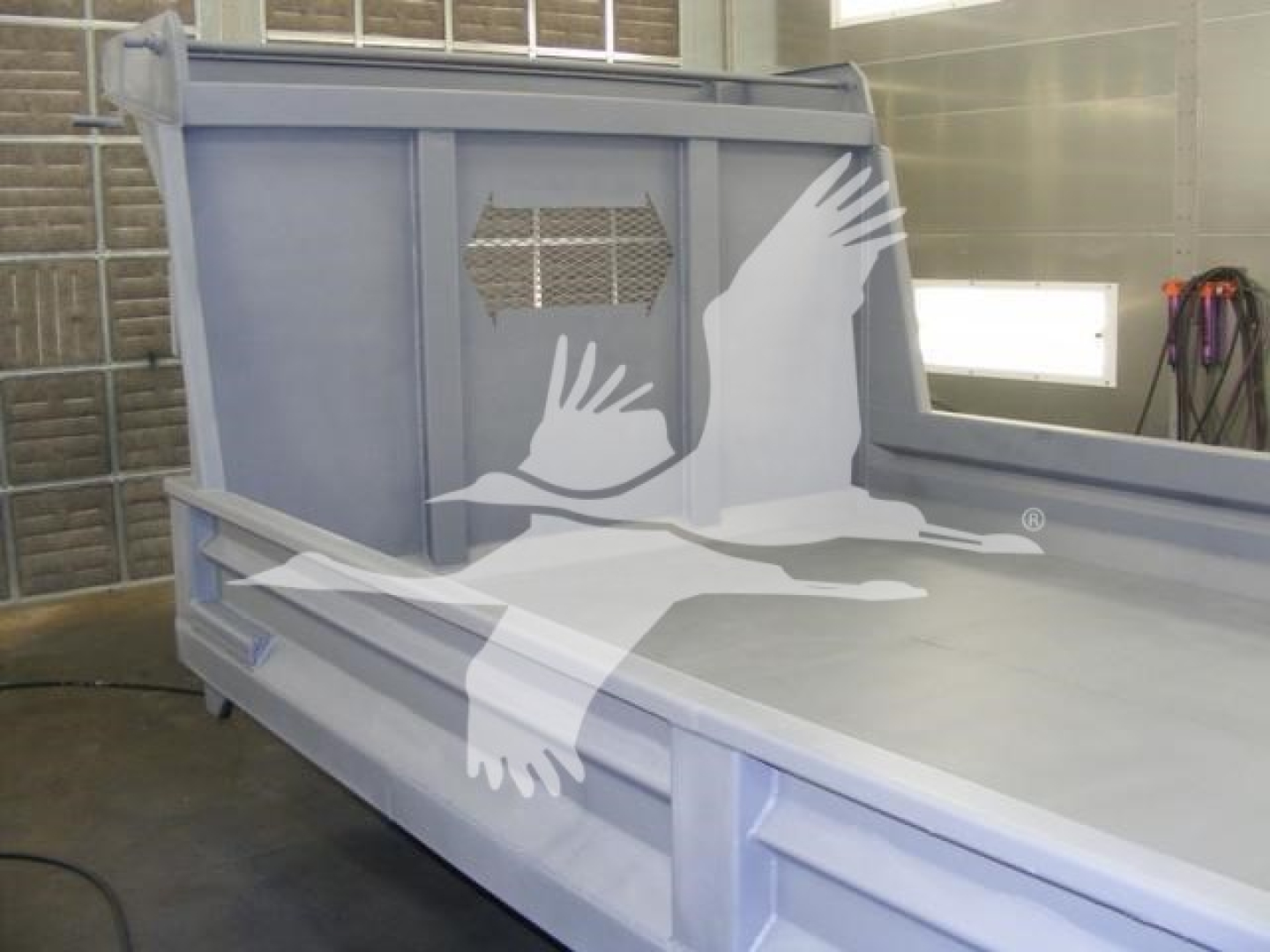 Dump truck bed side panel with carriage and rear wall; 14 ft Advanced Fabricators dump bed in workshop with protective cage and metal ribs visible.