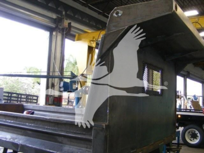 Industrial dump truck attachment with metal framework and cutout guard; no legible brand text visible.