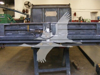 Dump truck bed shown in workshop with metal side walls and rear tailgate.