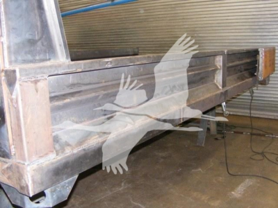 Dump truck bed side with metal construction and support rails, visible hydraulic lines and frame details.