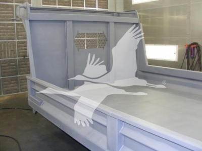 Dump truck bed side panel with carriage and rear wall; 14 ft Advanced Fabricators dump bed in workshop with protective cage and metal ribs visible.