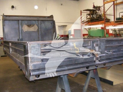 Dump truck bed of a 2026 Advanced Fabricators 14 ft unit showing a metal dump bed with side panels and tailgate in a workshop.