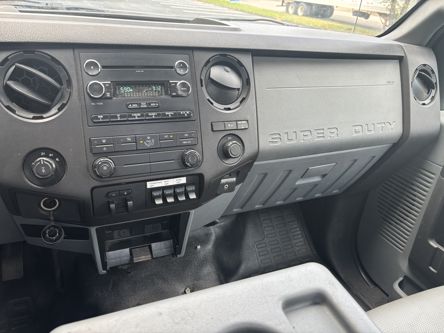 Ford F-250 interior dashboard view showing center stack with radio, climate controls, two circular vents, and 'SUPER DUTY' embossed on passenger side glove area.