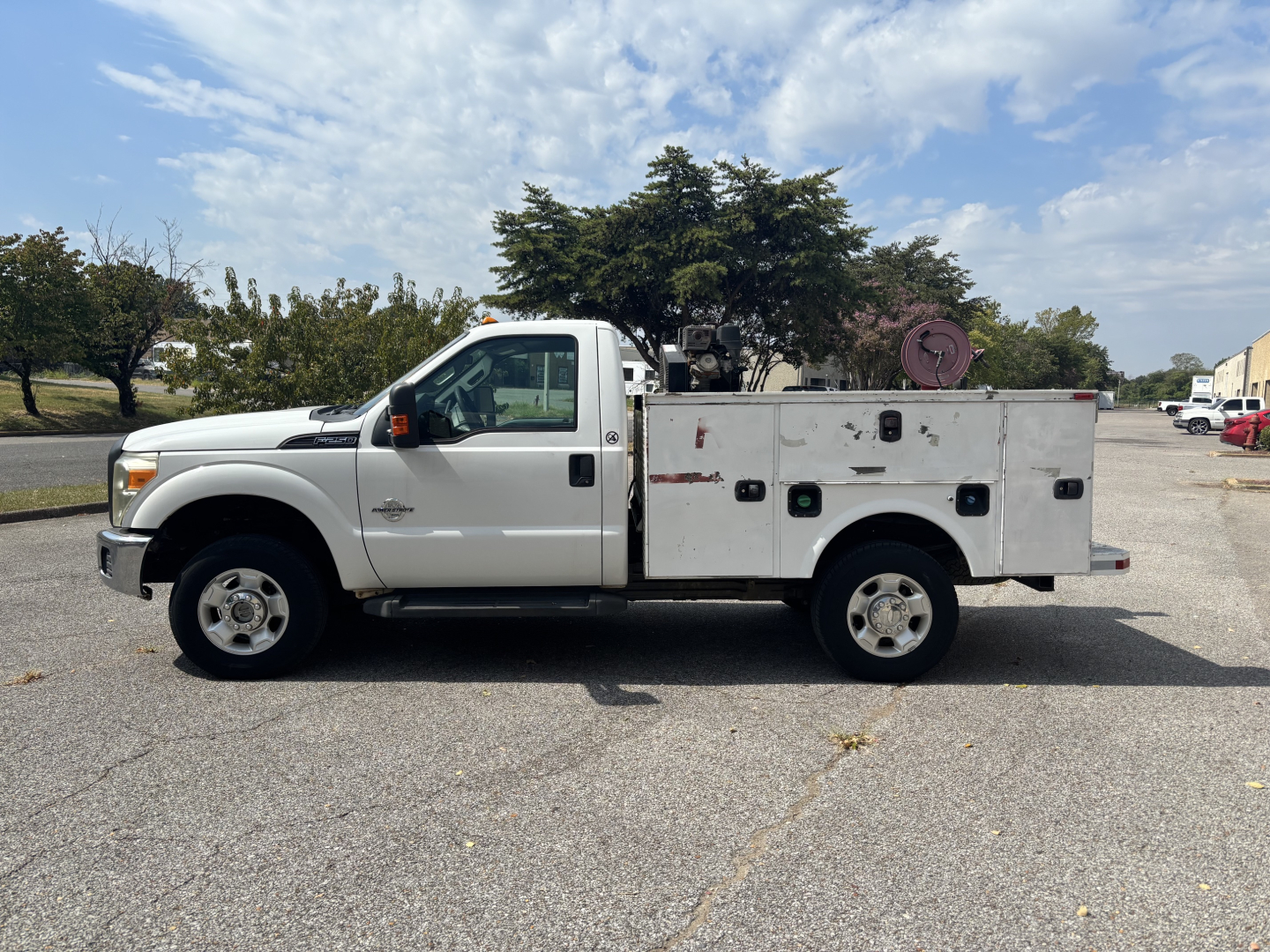 Side view of a white 2012 Ford F-250 service utility truck with utility bed compartments and equipment on top, showing VIN and stock info context.