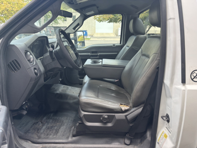 Ford F-250 interior driver seat with steering wheel, dashboard, and center console. Front seats show wear on the driver's seat; cab area visible.