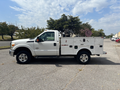 Side view of a white 2012 Ford F-250 service utility truck with utility bed compartments and equipment on top, showing VIN and stock info context.