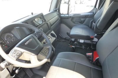 Freightliner truck cab interior showing steering wheel, dashboard, and driver seat with modern controls.