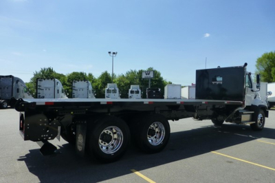 Flatbed truck chassis showing dual rear axles and a black tool/storage box toward cab; Freightliner 114Sd Plus likely new, VIN and stock not visible on image.