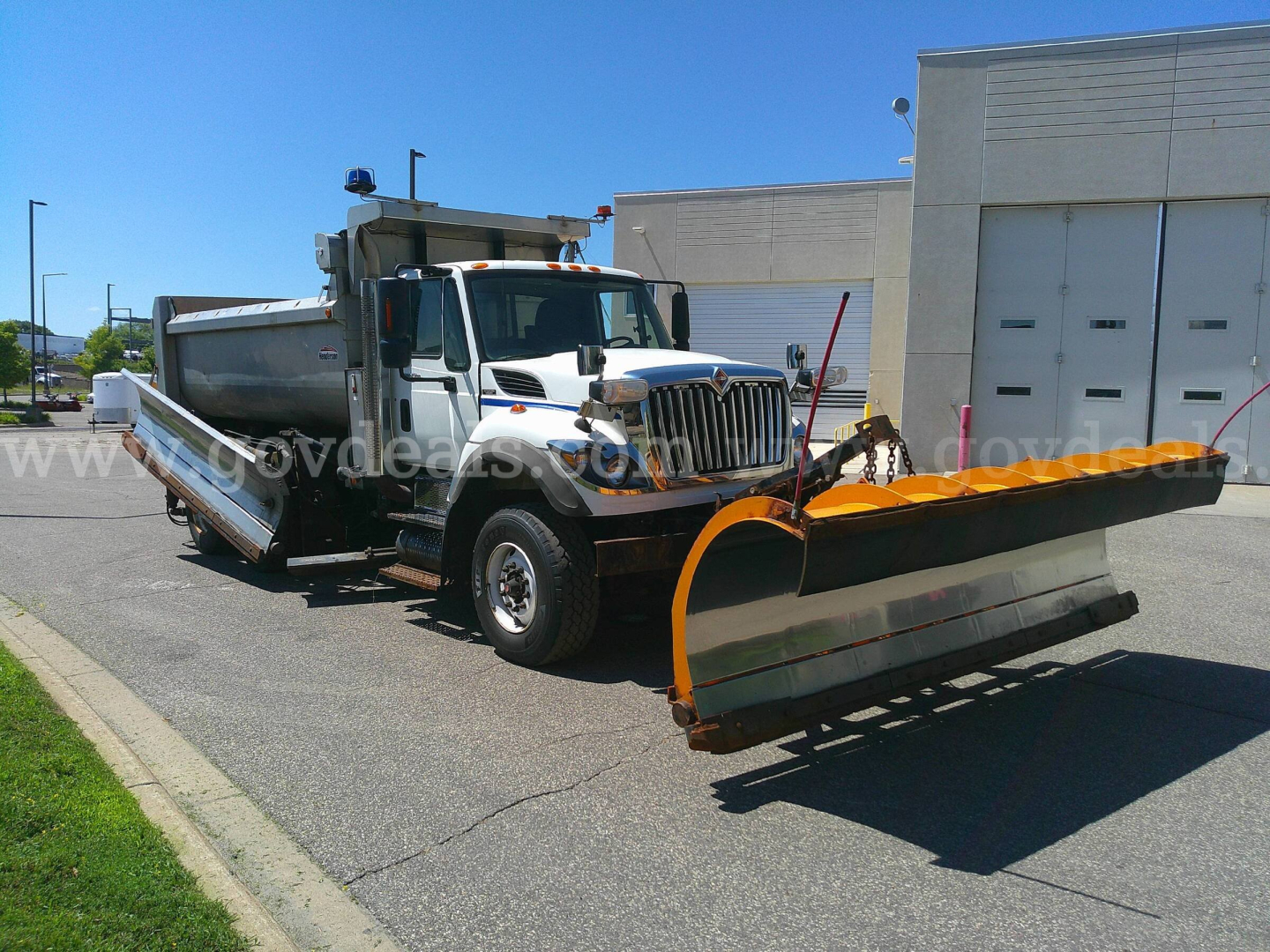 2008 International 7600 plow truck with large orange front snow plow and dual rear dump bed, shown in a parking lot.
