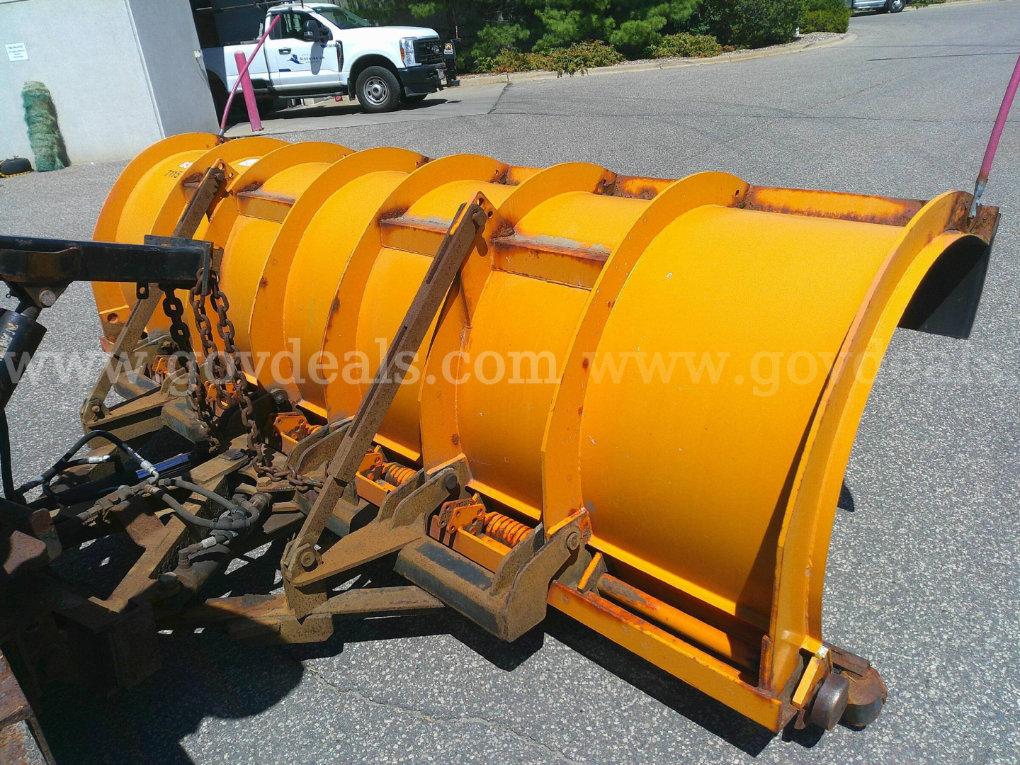 Industrial snow plow blade attachment on International truck, yellow steel curved blade with mounting frame and hydraulic linkage.