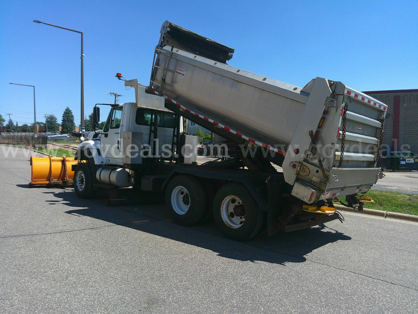 Dump truck with rotating dump bed and plow attachment in a parking lot, International 7600 series.