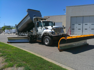 2008 International 7600 plow truck with dump bed raised, front view showing plow attachment and hydraulic system.