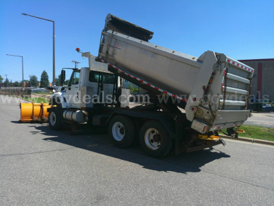 Dump truck with rotating dump bed and plow attachment in a parking lot, International 7600 series.