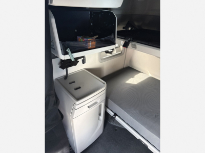 Volvo VNL 840 cab interior showing sleeper bunk and storage compartments with a small cabinet and a cooler or mini-fridge unit.