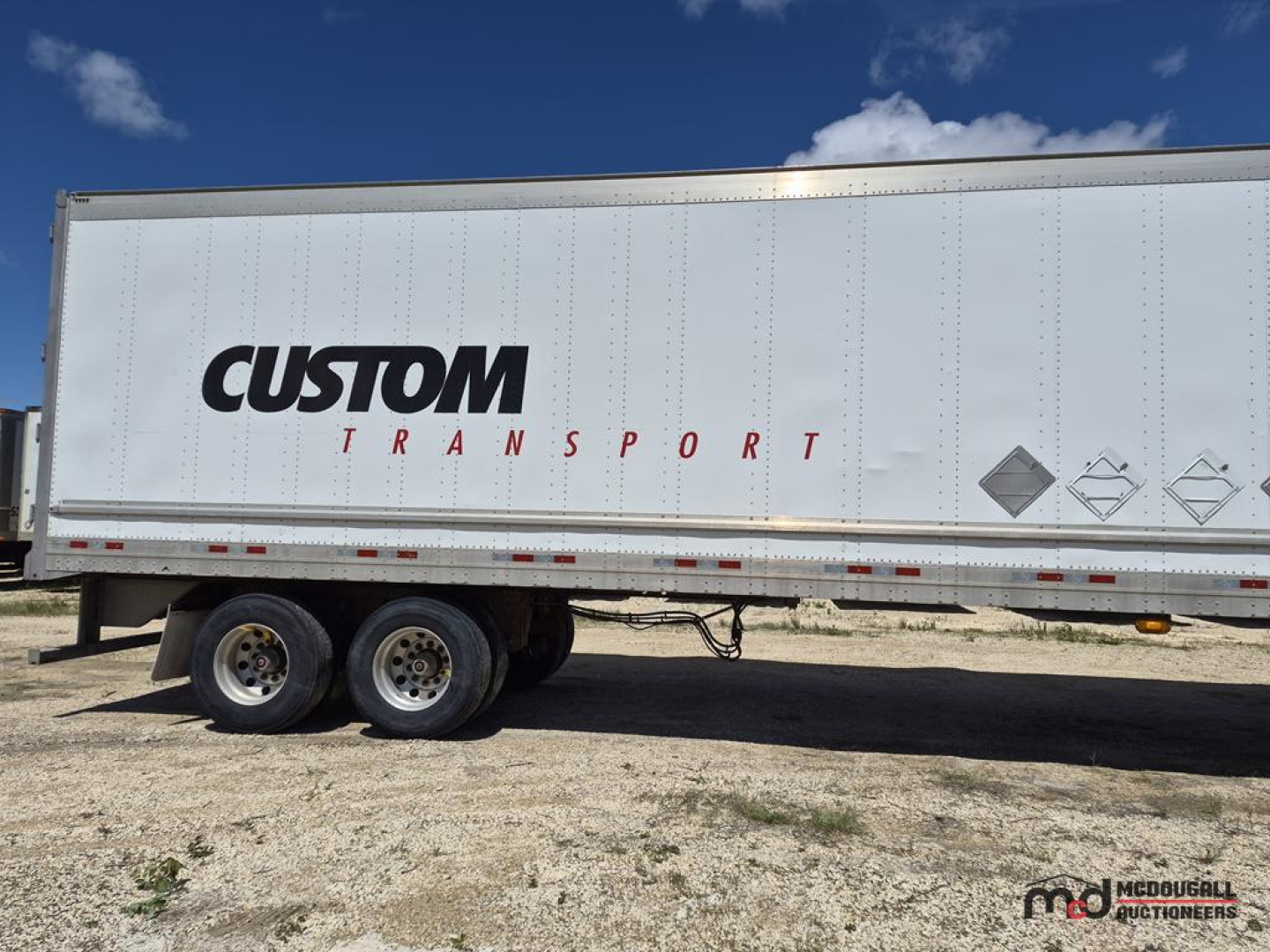 Trailer side showing CUSTOM TRANSPORT logo and warning diamonds on a 53' dry van trailer.