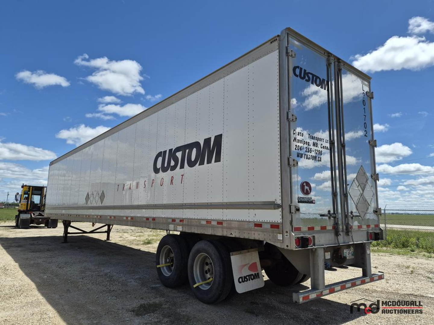 Trailer showing Custom Transport logo, rear doors, and dual-axle undercarriage on a dry van trailer.