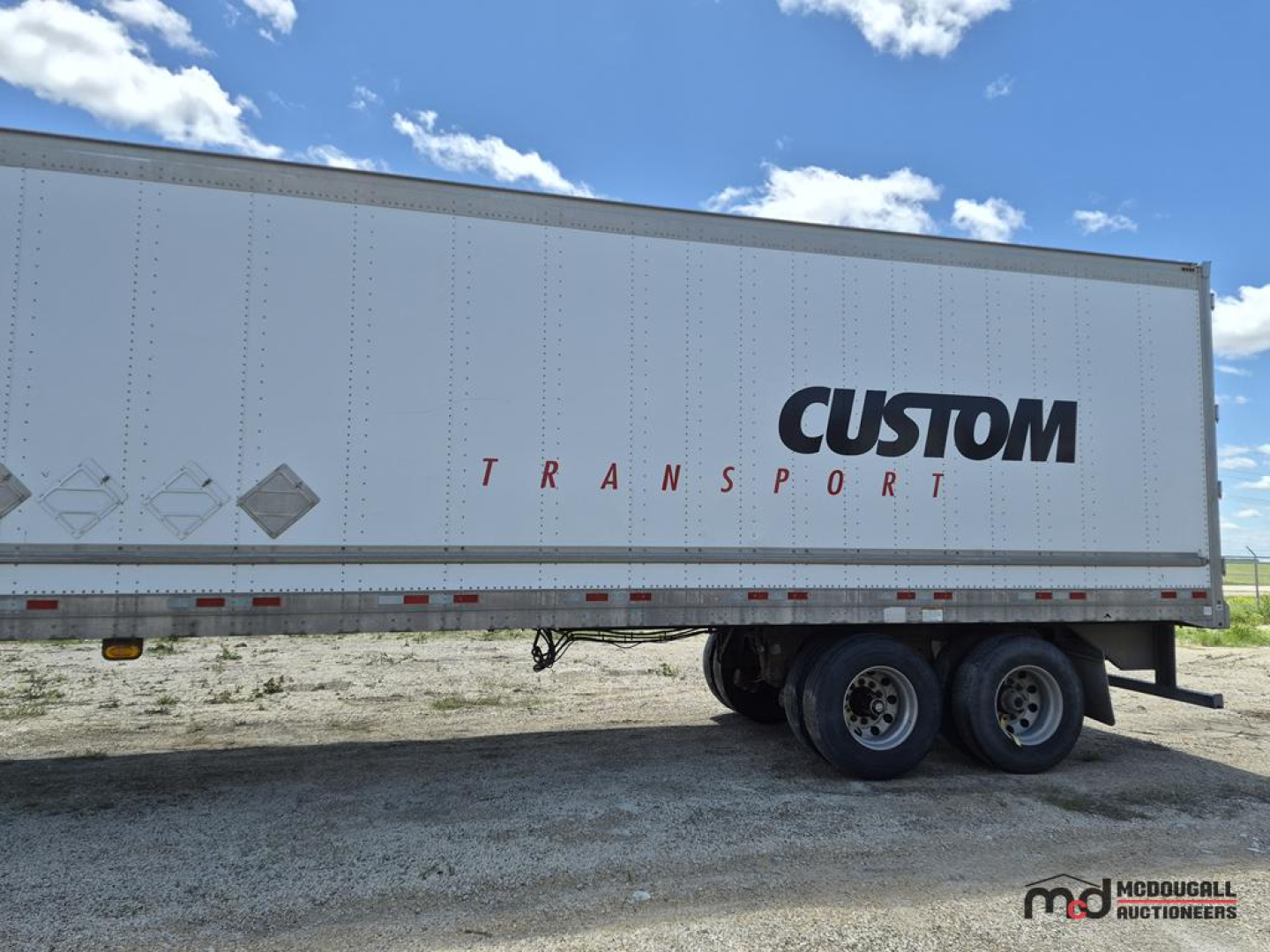 Great Dane 53' dry van semi trailer side view with CUSTOM TRANSPORT logo and twin rear axles; white trailer on gravel.