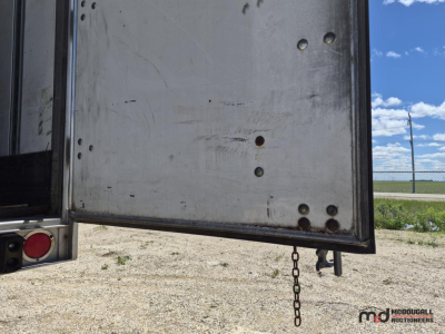Trailer rear door edge with chain and hinge pins visible, metal surface with scuffs and rivets.