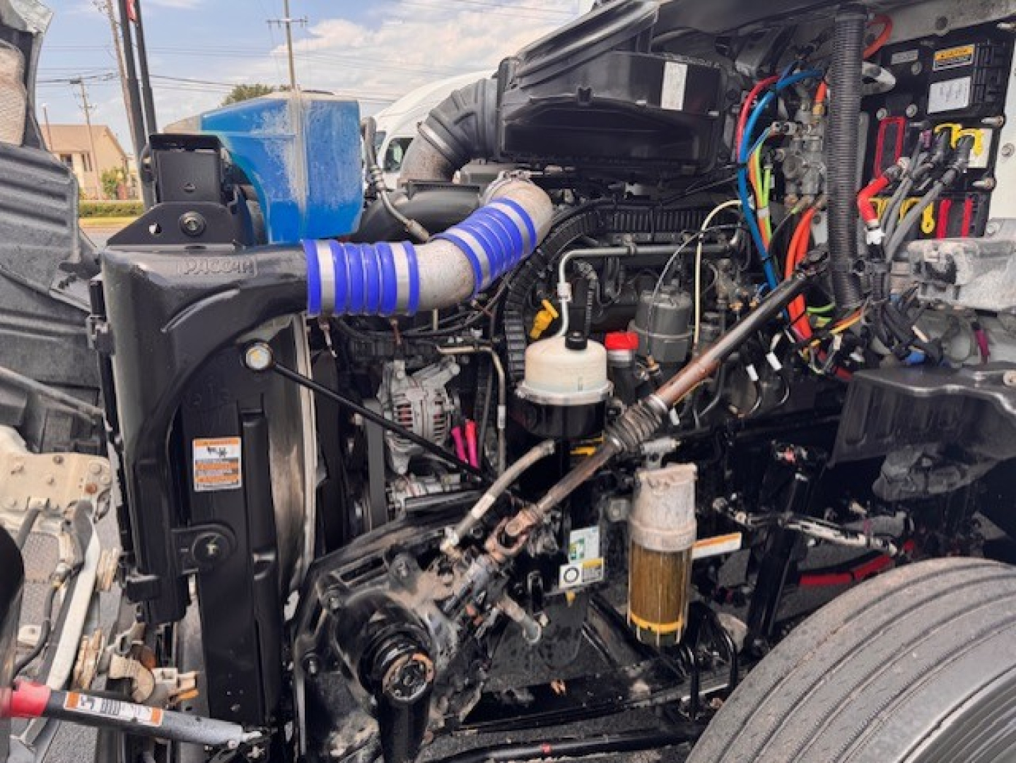 Truck engine bay of a 2021 Peterbilt 579 conventional daycab showing engine, hoses, wiring, and filter assemblies.