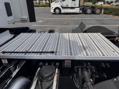 Peterbilt 579 truck chassis and diamond plate step showing fuel tank cap and mechanical components.