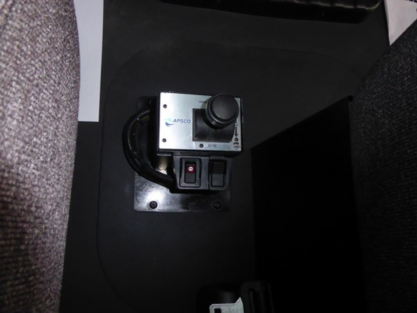 Switcher lever with APSCO device mounted in a console area, shows a metallic control box with a black joystick-like knob and a red/black toggle switch nearby.